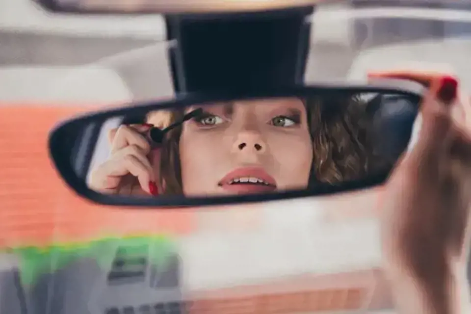 Ayna karşısında aura rengine uygun makyaj yapan kadın